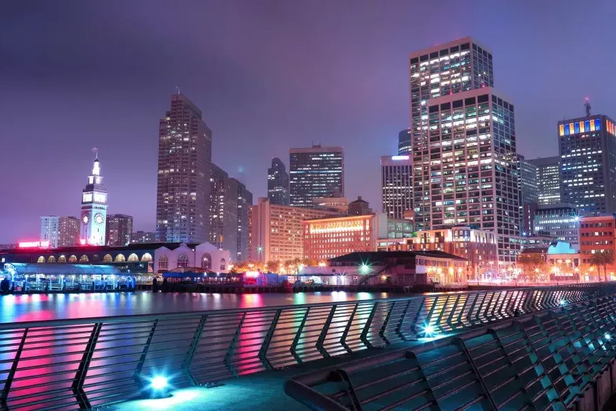 Der Embarcadero in San Francisco ist nachts in verschiedenen Pastellfarben beleuchtet.